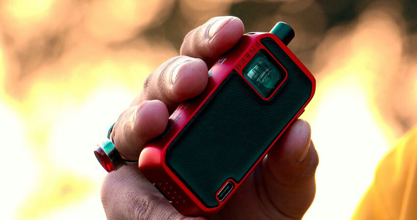 close up view of a hand holding a red and black vape